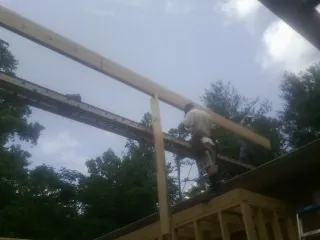Carpenter setting a ridge beam over a new addition frame — Ice Dam Removal by Roofing Brothers in Kirksville