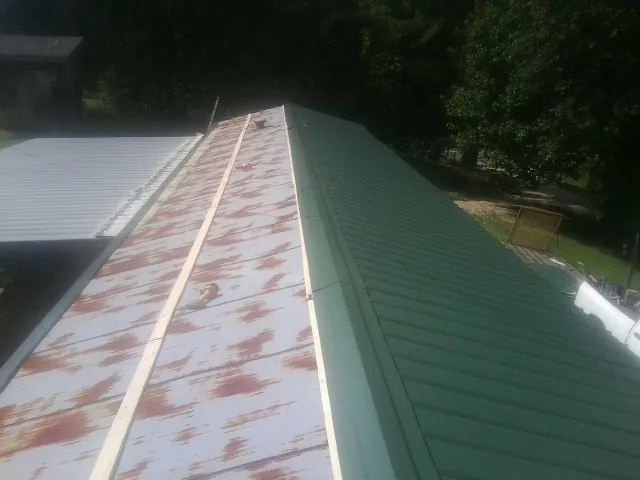 Old rusted panels beside newly installed green metal roofing — Wind Damage Roof Repair by Roofing Brothers in Kirksville