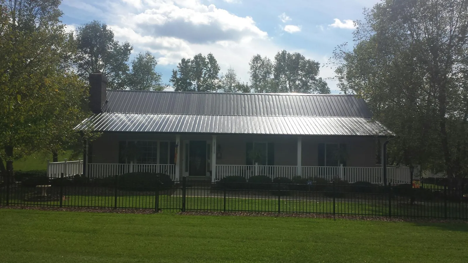 Gray metal roof on a brick ranch with a full width front porch — Gutter Guard Installation work by our crew in Kirksville