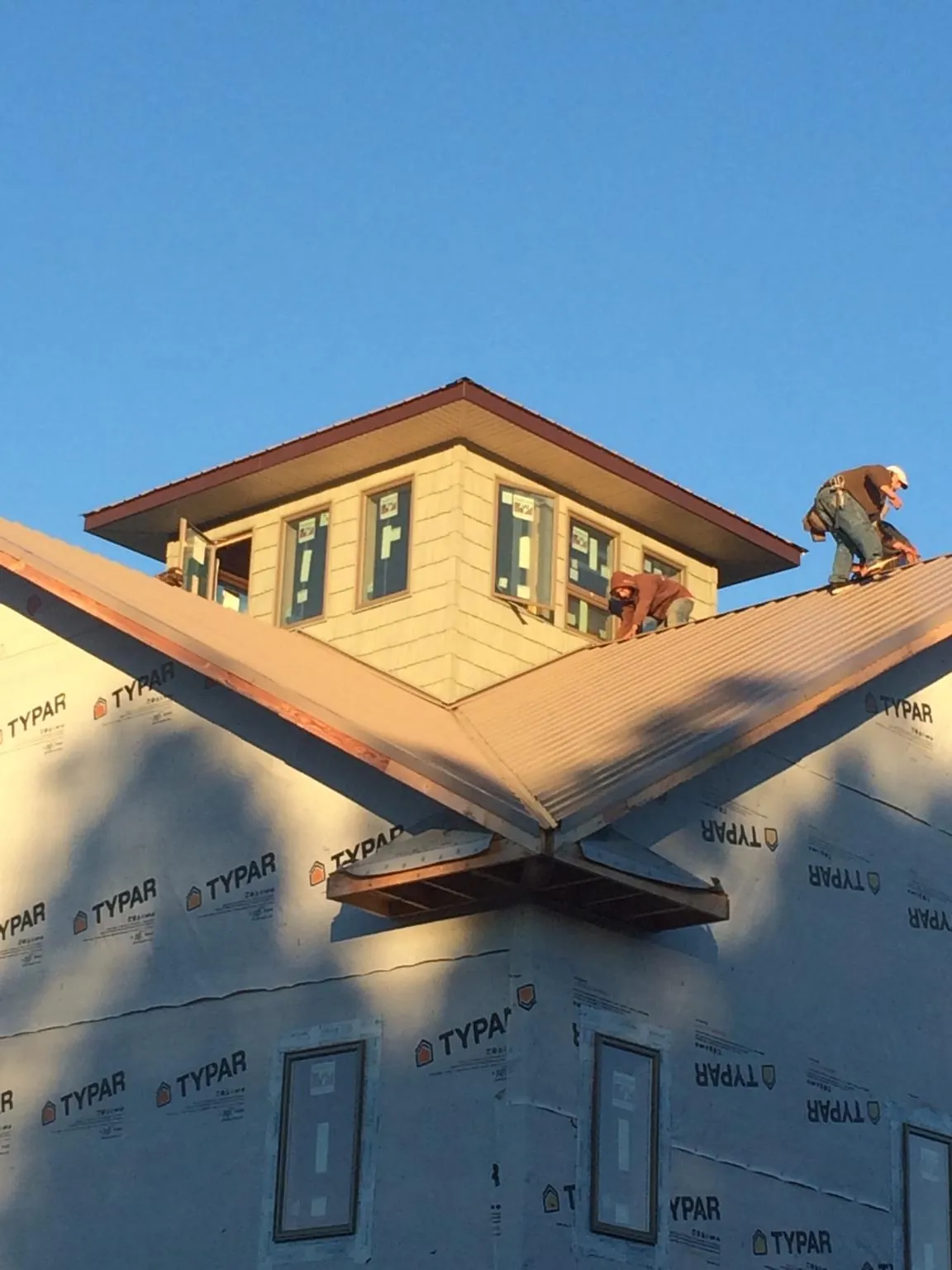 Roofers working around a rooftop cupola on a new metal roof at sunset — Roof Waterproofing in Kirksville by Roofing Brothers